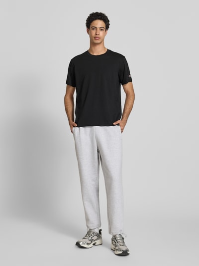 Männermodel trägt T-Shirt mit Rundhalsausschnitt im 2er-Pack von CHAMPION in Schwarz, Reine Baumwolle, Regular-Fit, Label-Detail, Ganzkörperansicht von vorne.