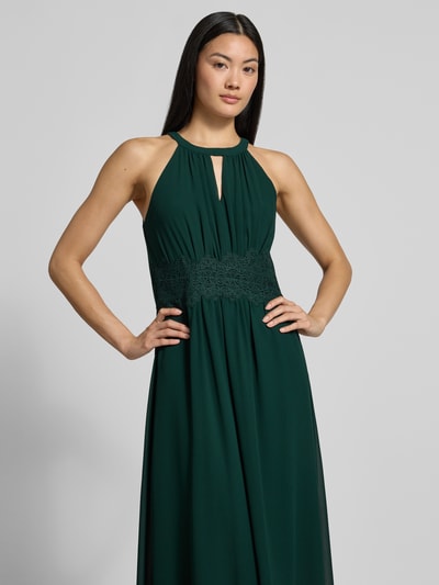 Vrouwenmodel draagt avondjurk met tailleband Model 'MILINA' van VILA in donkergroen chiffon met druppelvormige hals, getailleerd model, Maxi-jurk; context: dames avondjurk, hals met halter, ruglengte maat 36: 146 cm, borstwijdte maat 36: 35 cm. Nahaufnahme Oberkörper.