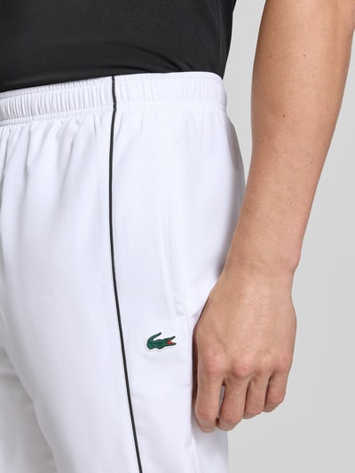 Männermodel trägt weiße Regular Fit Trainingshose mit Logo-Patch von Lacoste, Herren Trainingshose, Nahaufnahme Hüfte.