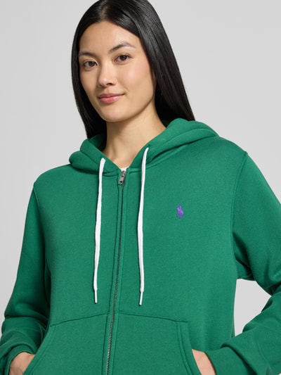 Frauenmodel trägt Regular Fit Sweatjacke aus Baumwoll-Mix von Polo Ralph Lauren in Grün mit lila Logo, Nahaufnahme Oberkörper, Damen Sweatjacke von Polo Ralph Lauren.