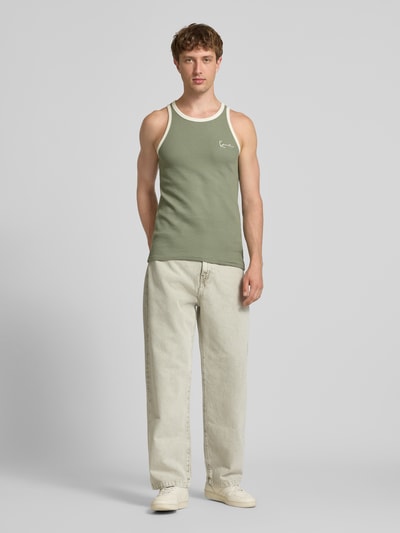 Męski model nosi Slim Fit Top mit Logo-Stitching od KARL KANI z czystej bawełny, krój slim fit, teksturowany wzór, okrągły dekolt, długość tyłu w rozmiarze M: 68 cm, zielony z białymi akcentami, widok całej sylwetki z przodu.