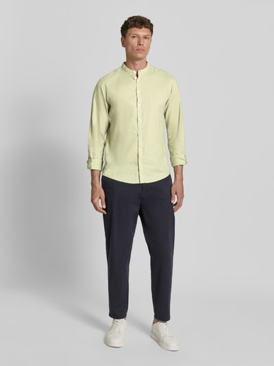 Männermodel trägt hellgrünes Slim Fit Freizeithemd mit Stehkragen Modell 'Anton' von Casual Friday aus Seide-Baumwoll-Mix, Knopfleiste, Label-Stitching, kombiniert mit dunkelblauer Hose, lässig und modern, Ganzkörperansicht von vorne.