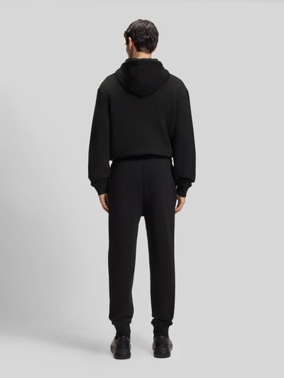 Männermodel trägt Regular Fit Jogginghose aus reiner Baumwolle Modell 'DAYOTE232' von HUGO in Schwarz, Ganzkörperansicht Rückansicht.