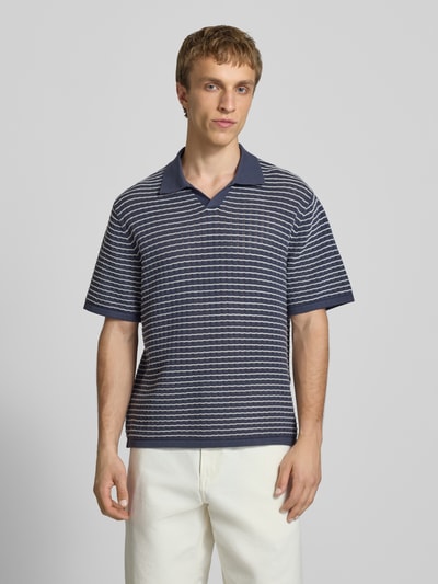 Männermodel trägt Regular Fit Poloshirt mit V-Ausschnitt von Jack & Jones aus reiner Baumwolle, Strickshirt, gestreift, Ganzkörperansicht von vorne. Rückenlänge bei Größe M: 67 cm.