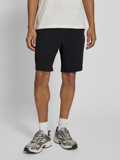 Männermodel trägt Regular Fit Sweatshorts aus reiner Baumwolle Modell 'DAYONO' von HUGO, unifarben schwarz, Ganzkörperansicht von vorne.