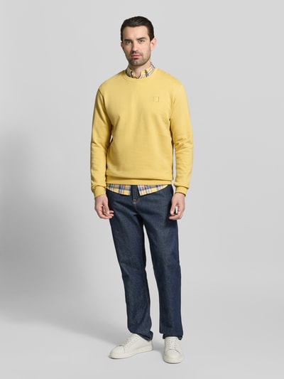 Männermodel trägt Sweatshirt mit Rundhalsausschnitt von Scotch & Soda, Reine Baumwolle, Regular-Fit, Label-Stitching, gelb. Ganzkörperansicht von vorne.