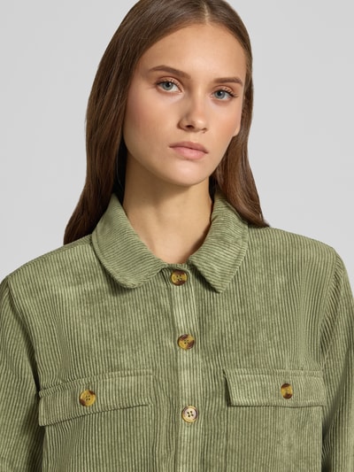 Frauenmodel trägt Relaxed Fit Langarmbluse in Cord-Optik Modell 'EFFI' von PIECES in Hellgrün mit Knopfleiste und Brusttaschen, Nahaufnahme Oberkörper. Damen Langarmbluse von PIECES.