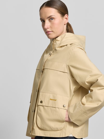Frauenmodel trägt Regular Fit Funktionsjacke aus Baumwoll-Mix Modell 'BAYTHORPE' von Barbour, Optik: Unifarben, Kapuze, Label-Stitching, Pattentaschen, Funktion: Wasserdicht, Atmungsaktiv, Farbe Beige, glatte Textur, Nahaufnahme Oberkörper