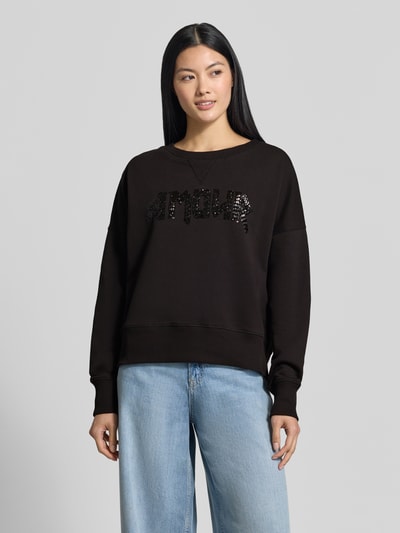 Frauenmodel trägt Relaxed Fit Sweatshirt aus reiner Baumwolle von miss goodlife in Schwarz mit Paillettenbesatz und Statement-Design, Rundhalsausschnitt, elastische Abschlüsse, Ganzkörperansicht von vorne.