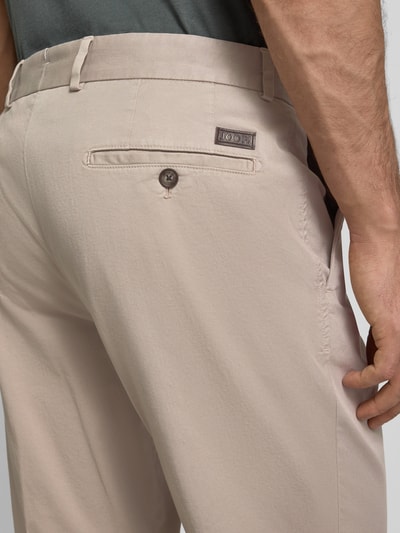 Männermodel trägt Stoffhose mit Gesäßtaschen Modell 'Hank' von JOOP! Collection aus Baumwoll-Elasthan-Mix, Detailaufnahme Hüfte.
