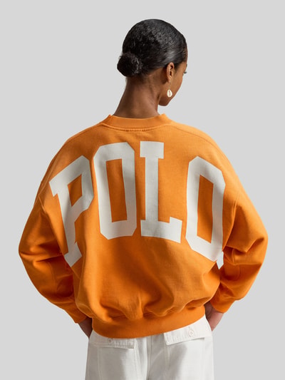 Frauenmodel trägt Oversized Sweatshirt aus Baumwoll-Mix von Polo Ralph Lauren in Orange, unifarben mit Logo-Stitching, Ganzkörperansicht Rückansicht.