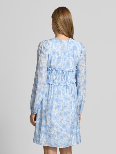 Vrouwenmodel draagt knielange dames jurk van viscosemix model 'Pipiana' van mbyM met all-over bloemenprint, getailleerde pasvorm, met lange mouwen, ruches, v-hals, elastische mouwboorden, ruglengte maat S 93 cm, borstwijdte maat S 40 cm, mouwlengte maat S 65 cm. Ganzkörperansicht Rückansicht.