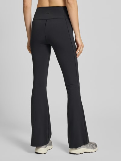 Frauenmodel trägt Flared Fit Stoffhose mit breitem Bund Modell 'All Me' von adidas Sportswear, schwarz, glatte Oberfläche, Ganzkörperansicht Rückansicht.
