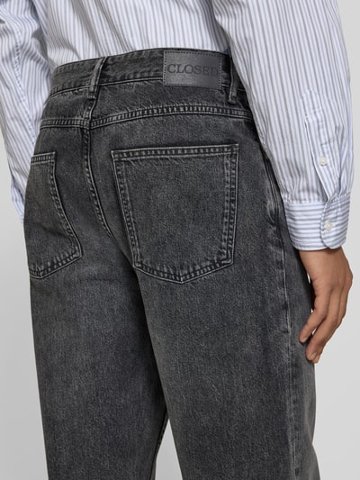 Männermodel trägt Jeans mit 5-Pocket-Design von Closed aus reiner Baumwolle, Relaxed Fit, Label-Detail, Detailaufnahme Rückansicht.