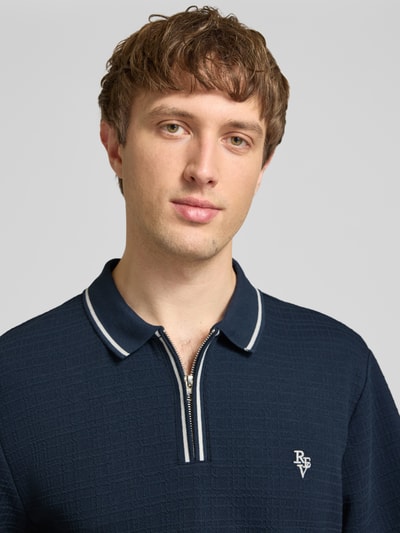Männermodel trägt Regular Fit Poloshirt mit Reißverschluss und Label-Stitching von REVIEW, dunkelblau mit Strukturmuster, Nahaufnahme Oberkörper.
