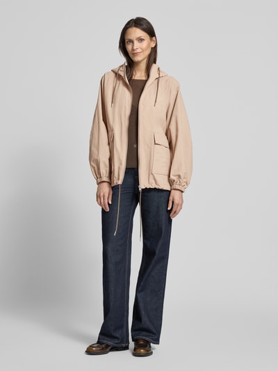 Vrouwenmodel draagt Jacke met kapuze en klepzakken van Jake*s Casual, relaxed fit, ritssluiting, tunnelkoord, ruglengte maat 36: 66 cm, schouderbreedte: 41 cm, borstwijdte: 56 cm, mouwlengte: 65 cm, lichte beige tint, donkerbruine top, donkerblauwe jeans, donkerbruine schoenen, zachte textuur, klepzakken, capuchon, frontale lichaamsaanzicht.