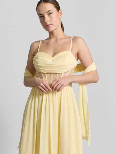 Frauenmodel trägt Corsagenkleid mit Spitze von Mascara in zartgelbem Chiffon, taillierter Schnitt, Spitze, Nahaufnahme Oberkörper.