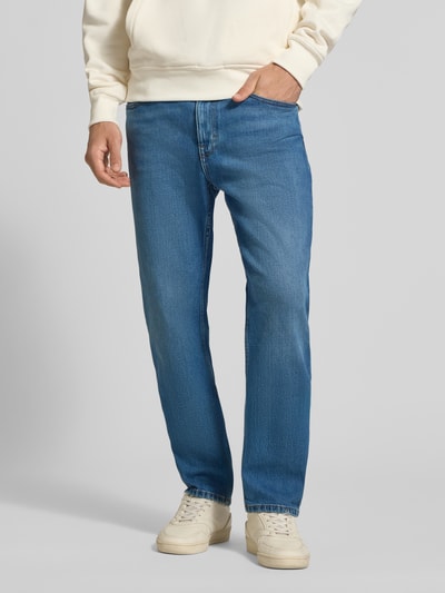 Männermodel trägt Slim Straight Fit Jeans aus Baumwoll-Mix Modell 'RYAN' von Tommy Jeans in klassischem Denim-Blau, Kontrastnähte, Mid Waist, 5-Pocket-Design, Ganzkörperansicht von vorne.