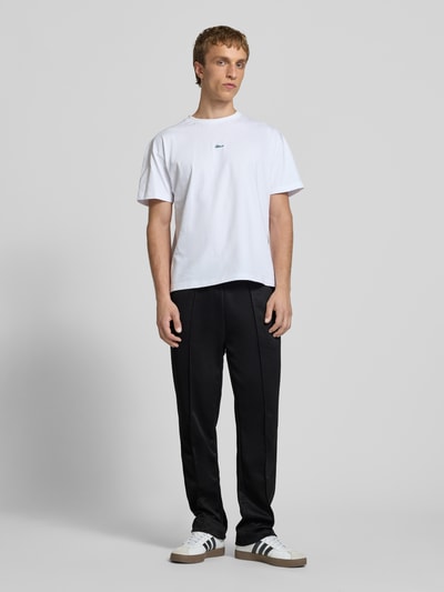 Męski model nosi spodnie typu track pants z Längsnähten model 'Motus' od Pegador, mieszanka bawełny, krój relaxed fit, elastyczny pas, długość wewnętrzna nogawki w rozmiarze M: 75 cm, czarne, gładka faktura, Ganzkörperansicht von vorne.