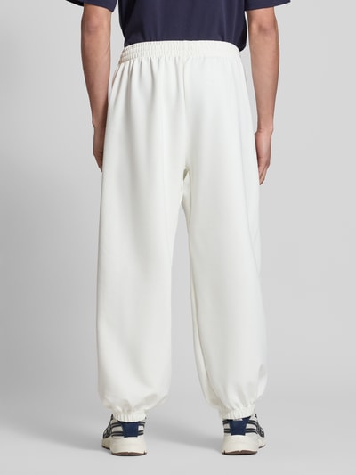 Männermodel trägt Regular Fit Sweatpants mit Modal-Baumwoll-Anteil von adidas Sportswear, unifarben weiß, Ganzkörperansicht Rückansicht.