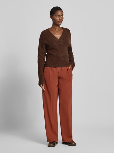Frauenmodel trägt Strickpullover in Wickel-Optik Modell 'Bondie Hope' von MSCH Copenhagen in Braun, V-Ausschnitt, Regular Fit, kombiniert mit weiter Hose, Ganzkörperansicht von vorne.
