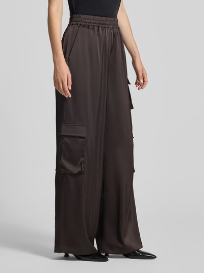 Frauenmodel trägt Loose Fit Stoffhose mit elastischem Bund Modell 'darzi' von Gestuz, brauner Material-Mix mit Stretch, Cargotaschen, Ganzkörperansicht von vorne.