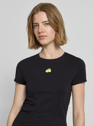 Frauenmodel trägt Slim Fit T-Shirt mit Motiv-Stitching von REVIEW, schwarzer Baumwoll-Mix, Rundhalsausschnitt, Rückenlänge 55 cm, Nahaufnahme Oberkörper.