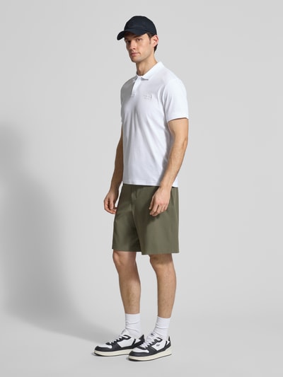Männermodel trägt Regular Fit Poloshirt aus reiner Baumwolle Modell 'PS Spirit 70 Plk' von BOSS Green X PORSCHE in Weiß, Ganzkörperansicht von vorne.