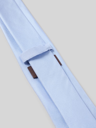 Produktfoto, Krawatte aus reiner Seide von Blick in Hellblau mit Strukturmuster, Teilungsnähte und Label-Detail auf grauem Hintergrund.