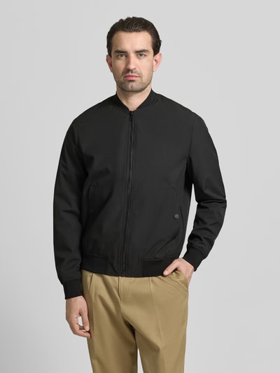 Mannelijk model draagt Regular Fit Bomberjacke mit Stehkragen van MCNEAL in zwart, elastische boorden en steekzakken, ganzebodyvoorzicht.