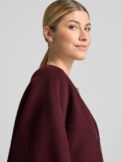Vrouwenmodel draagt Doubleface Wolljacke mit abnehmbarer Steppkapuze van Blonde No. 8 in wijnrood, Wolmix, relaxed fit, Nahaufnahme zijaanzicht. Ruglengte maat 36: 61 cm, Schouderbreedte: 52 cm, Borstwijdte: 67 cm, Mouwlengte: 54 cm, tweewegritssluiting, elastische mouwboorden.