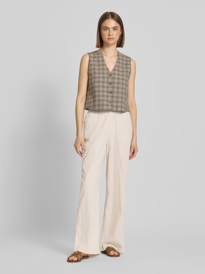 Frauenmodel trägt Wide Fit Stoffhose mit elastischem Bund Modell 'Poppy' von JJXX in Creme mit Eingrifftaschen, leichte Stoffstruktur, Ganzkörperansicht von vorne.