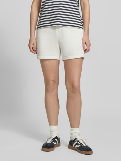 Kobiece modelka nosi Sweatshorts mit Eingrifftaschen und Label-Stitching von Gant, biały kolor, krój regular fit, bawełniana mieszanka, elastyczny pas, kieszenie, szerokość w rozmiarze S 36 cm, długość wewnętrzna nogawki 10 cm, widok całej sylwetki z przodu.