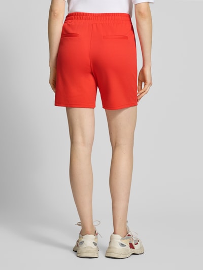 Vrouwenmodel draagt rode shorts met elastische band model 'Kate' van ICHI, materiaalmix met viscose, regular fit, binnenbeenlengte 18 cm, bandwijdte maat S 39 cm. Ganzkörperansicht Rückansicht.