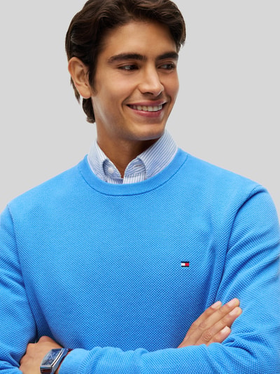 Mannelijk model draagt Regular Fit Pullover aus reiner Baumwolle van Tommy Hilfiger in helderblauw, gestructureerde textuur, Nahaufnahme Oberkörper.