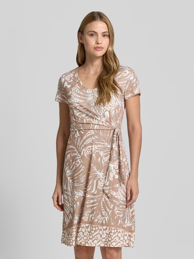 Frauenmodel trägt Knielanges Kleid in Wickel-Optik von More & More in Beige mit weißem Allover-Look, Material-Mix mit Stretch-Anteil, Gerader-Schnitt, Ganzkörperansicht von vorne. Rückenlänge Größe 36: 97 cm, Brustweite: 36 cm, Ärmellänge: 16 cm.
