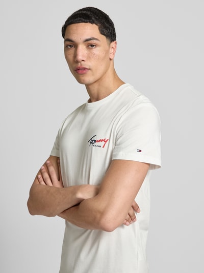 Männermodel trägt Slim Fit T-Shirt aus reiner Baumwolle von Tommy Jeans in Optik: Unifarben mit Label-Print und Logo-Stitching, Kurzarm, Rundhals, Nahaufnahme Oberkörper.