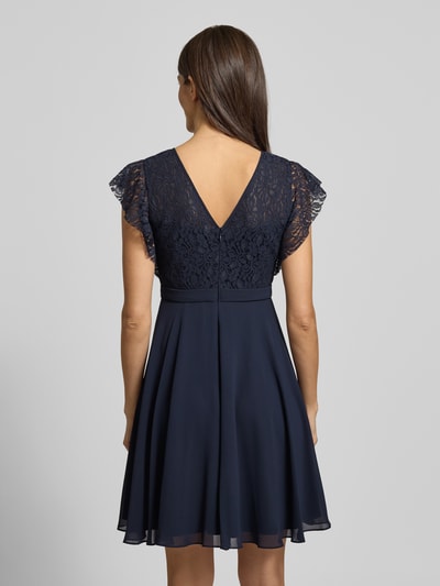 Frauenmodel trägt Knielanges Cocktailkleid mit Rundhalsausschnitt von Jake*s Cocktail in Dunkelblau, taillierter Schnitt, Rückansicht, Ganzkörperansicht.