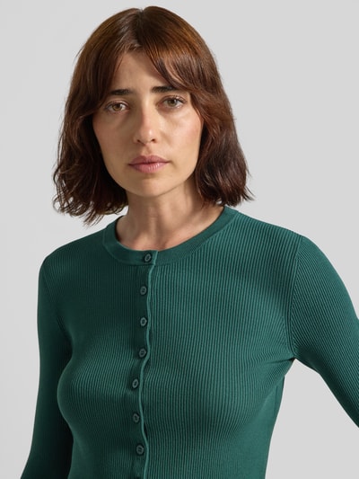 Frauenmodel trägt Slim Fit Strickjacke aus Viskose-Mix Modell 'WKDTENNIS' von Weekend Max Mara in grün, feine Rippenstruktur, Nahaufnahme Oberkörper. Damen Strickjacke von Max Mara.