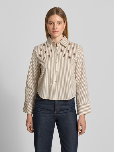 Kobiece model nosi Regular Fit Bluzkę w Allover-Look z perłami od Christian Berg Woman Selection, mieszanka bawełny z dodatkiem streczu, kołnierzyk koszulowy, listwa guzikowa, długość tyłu w rozmiarze 36: 59 cm, długość rękawów w rozmiarze 36: 61 cm, przód na całym zdjęciu, tło jasnoszare. Ganzkörperansicht von vorne.