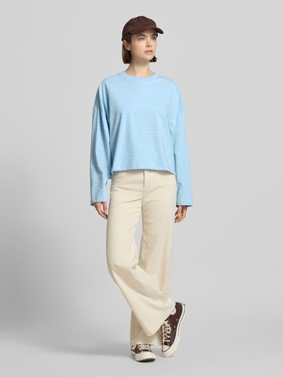 Frauenmodel trägt Longsleeve mit Rundhalsausschnitt von OH APRIL in Hellblau, lockerer Schnitt, reine Baumwolle, Ganzkörperansicht von vorne.
