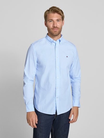 Männermodel trägt Body Fit Freizeithemd aus reiner Baumwolle von Tommy Hilfiger in Hellblau mit feinen Streifen, Ganzkörperansicht von vorne, Herren Freizeithemd von Tommy Hilfiger.