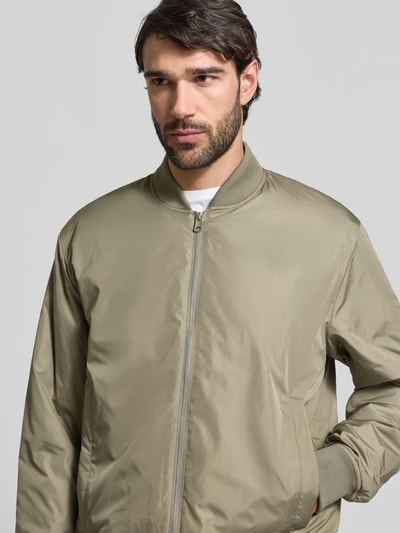Männermodel trägt Regular Fit Bomberjacke mit Zweiwege-Reißverschluss Modell 'CHRIS' von SELECTED HOMME, unifarben, Nahaufnahme Oberkörper.