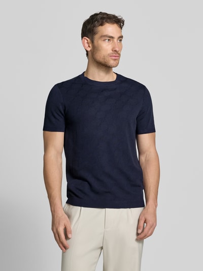 Männermodel trägt T-Shirt mit Viskose-Anteil und Rundhalsausschnitt Modell 'Ravao' von JOOP! Collection in Dunkelblau, Baumwoll-Viskose-Mix, Modern Fit, Label-Detail, Rückenlänge bei Größe M 69 cm, Ganzkörperansicht von vorne.
