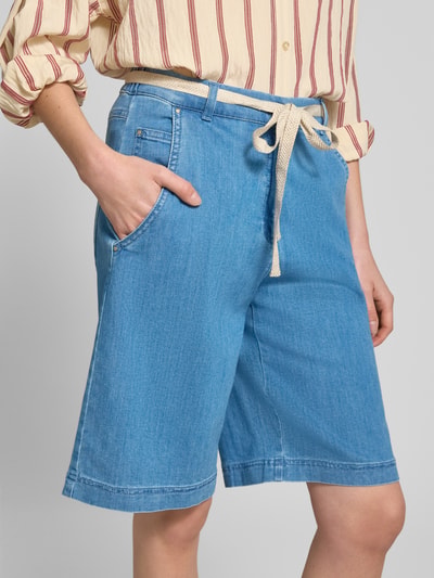 Frauenmodel trägt Wide Fit Bermuda aus Baumwoll-Mix von Raphaela By Brax in Denim-Optik mit Bindegürtel, seitlichen Eingrifftaschen, Nahaufnahme Oberkörper.