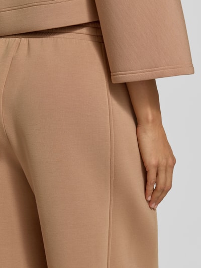 Mężczyznamodel nosi Wide Leg Sweathose aus Modal-Mix model 'GETTO' od Weekend Max Mara w kolorze beżowym, gładka tekstura, detal ręki, zbliżenie bok ciała.
