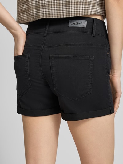 Frauenmodel trägt Regular Fit Jeansshorts aus Baumwoll-Mix Modell 'CARMEN' von Only in Schwarz mit Label Patch, 5-Pocket-Design, Ganzkörperansicht Rückansicht.
