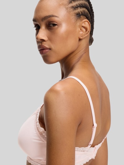 Frauenmodel trägt BH mit Spitzenbesatz Modell 'UNIQUE' von HUGO in zartem Rosa, Material-Mix mit Stretch, Nahaufnahme Oberkörper.