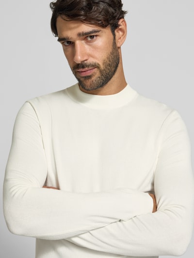 Męski model nosi Slim Fit Strickpullover aus Viskose-Mix mit Stehkragen von Antony Morato, kremowy kolor, prążkowane wykończenia, krój slim fit, mieszanka wiskozy, długość tyłu 65 cm, długość rękawów 64 cm, widok na górną część ciała z przodu.