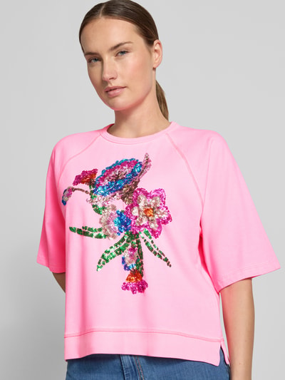 Frauenmodel trägt T-Shirt aus reiner Baumwolle von Milano Italy in Rosa mit Paillettenbesatz, lockere Passform, Nahaufnahme Oberkörper.
